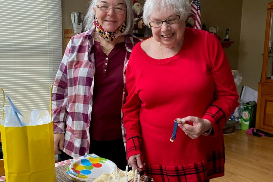 two women standing with a birthday cake